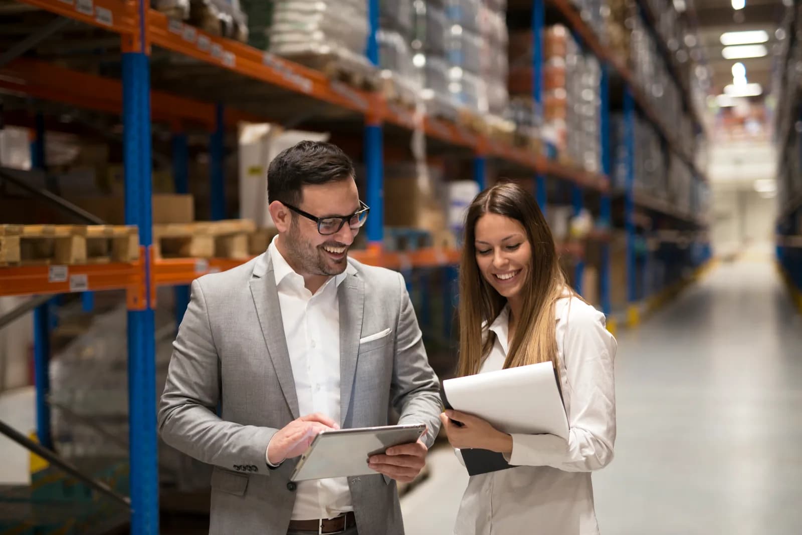 Operations managers reviewing distribution data on a tablet inside a warehouse